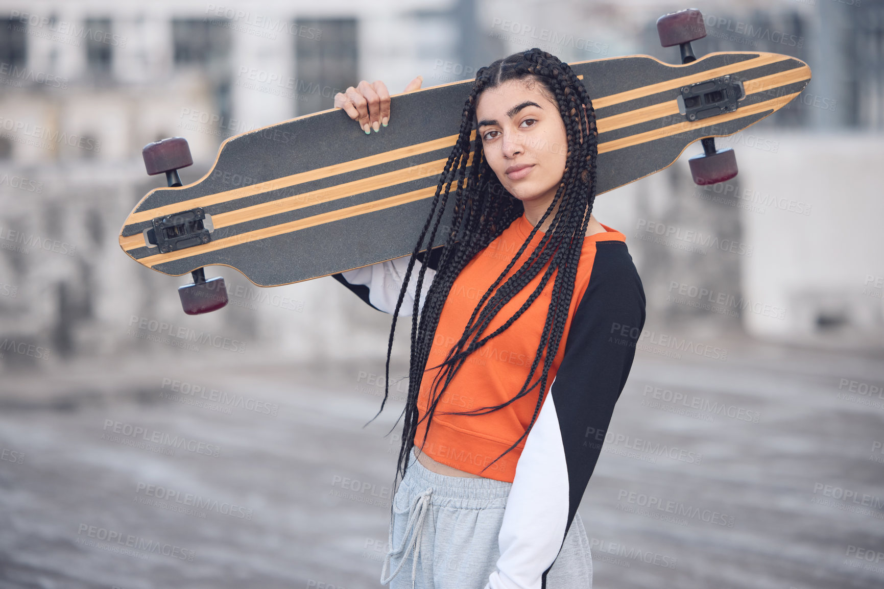 Buy stock photo Shot of a young woman out in the city with her skateboard