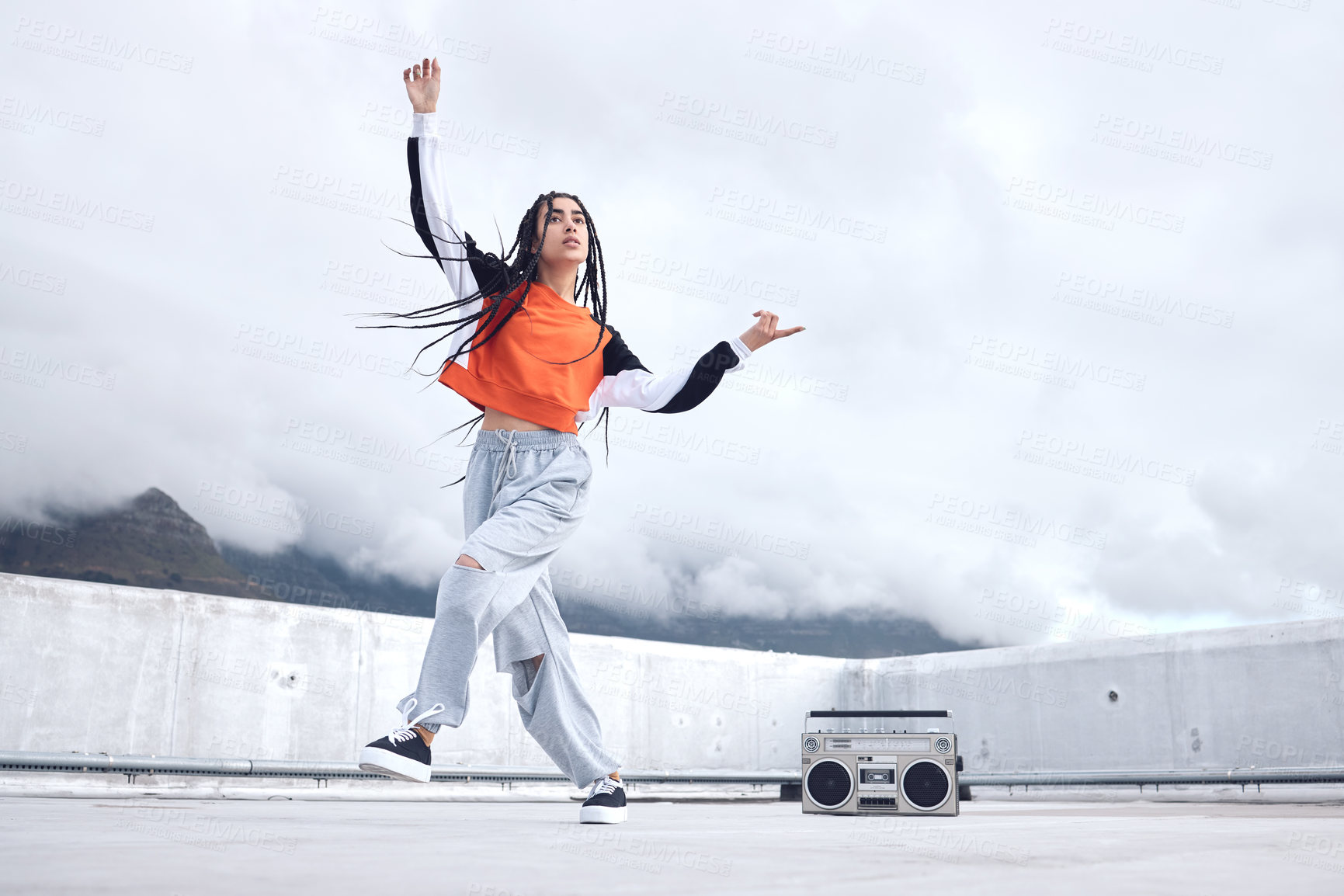 Buy stock photo Shot of a young woman out on a rooftop with a boombox