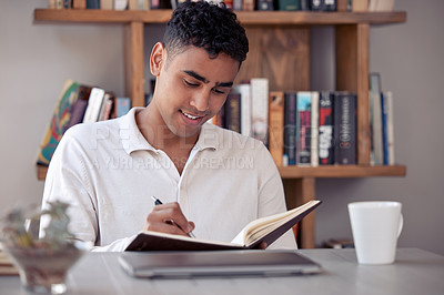 Buy stock photo Shot of an young male writing in his diary at home
