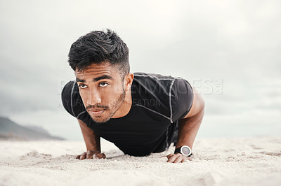 Buy stock photo Shot of a sporty young man doing push ups on the beach
