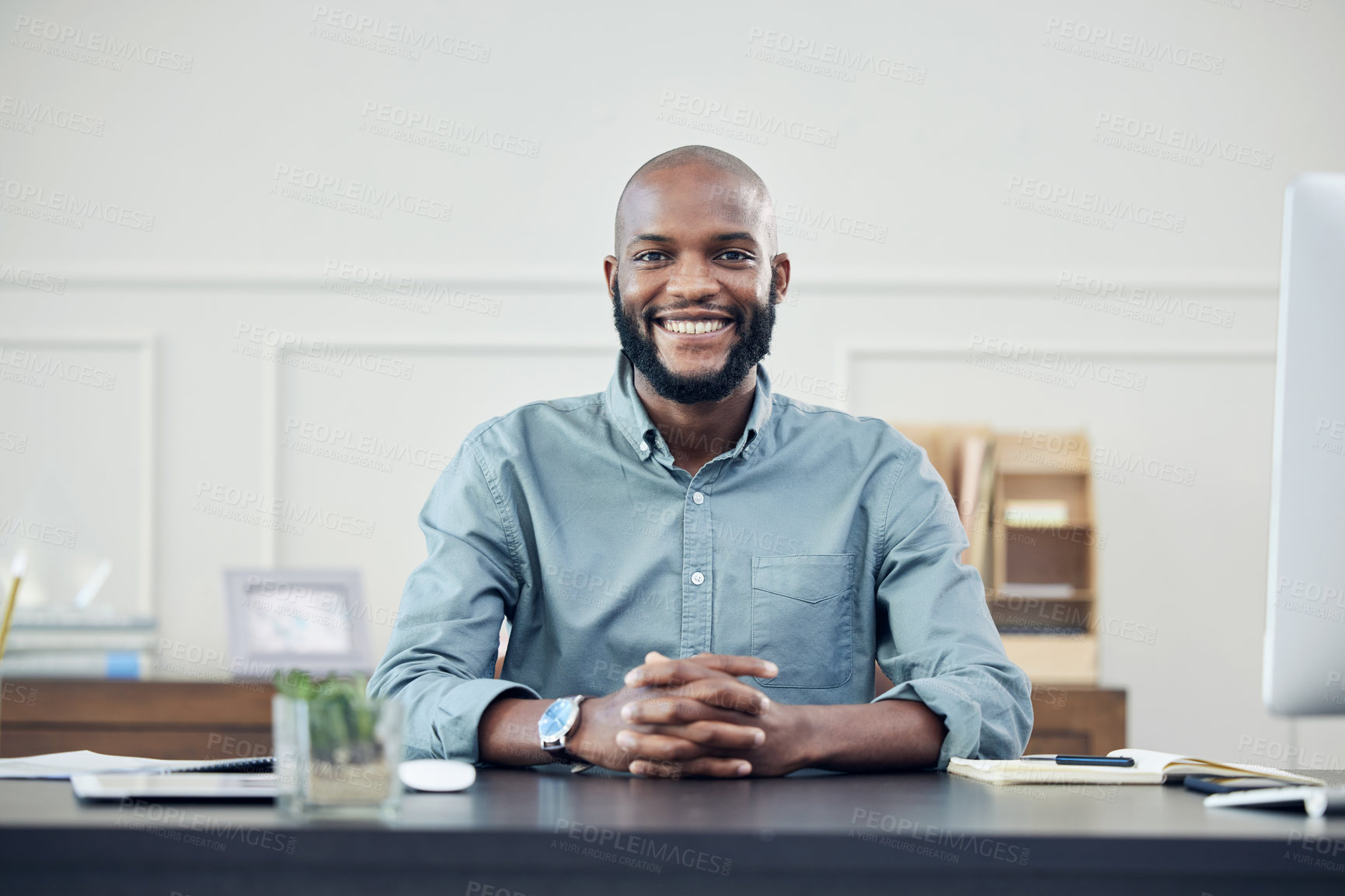 Buy stock photo Shot of a handsome young businessman sitting alone in his office during the day