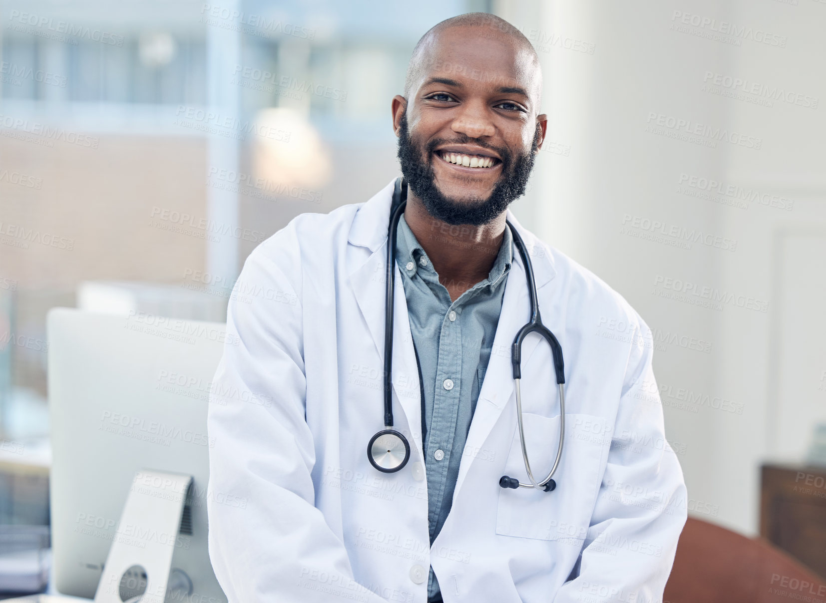 Buy stock photo Shot of a handsome young doctor standing alone in his clinic