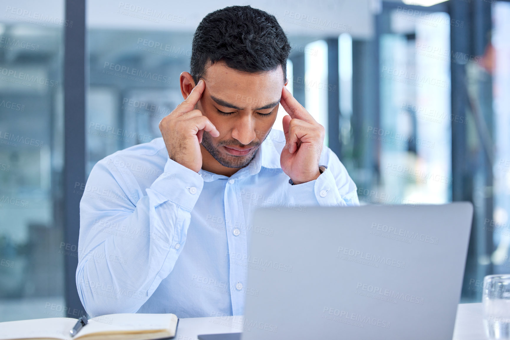 Buy stock photo Shot of a young businessman experiencing a headache at work