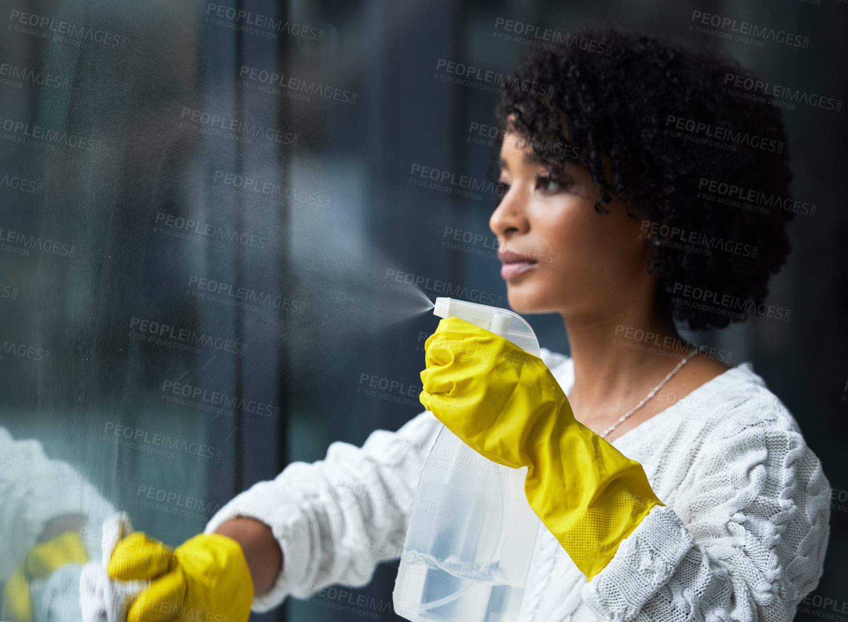 Buy stock photo Shot of a young woman cleaning her windows