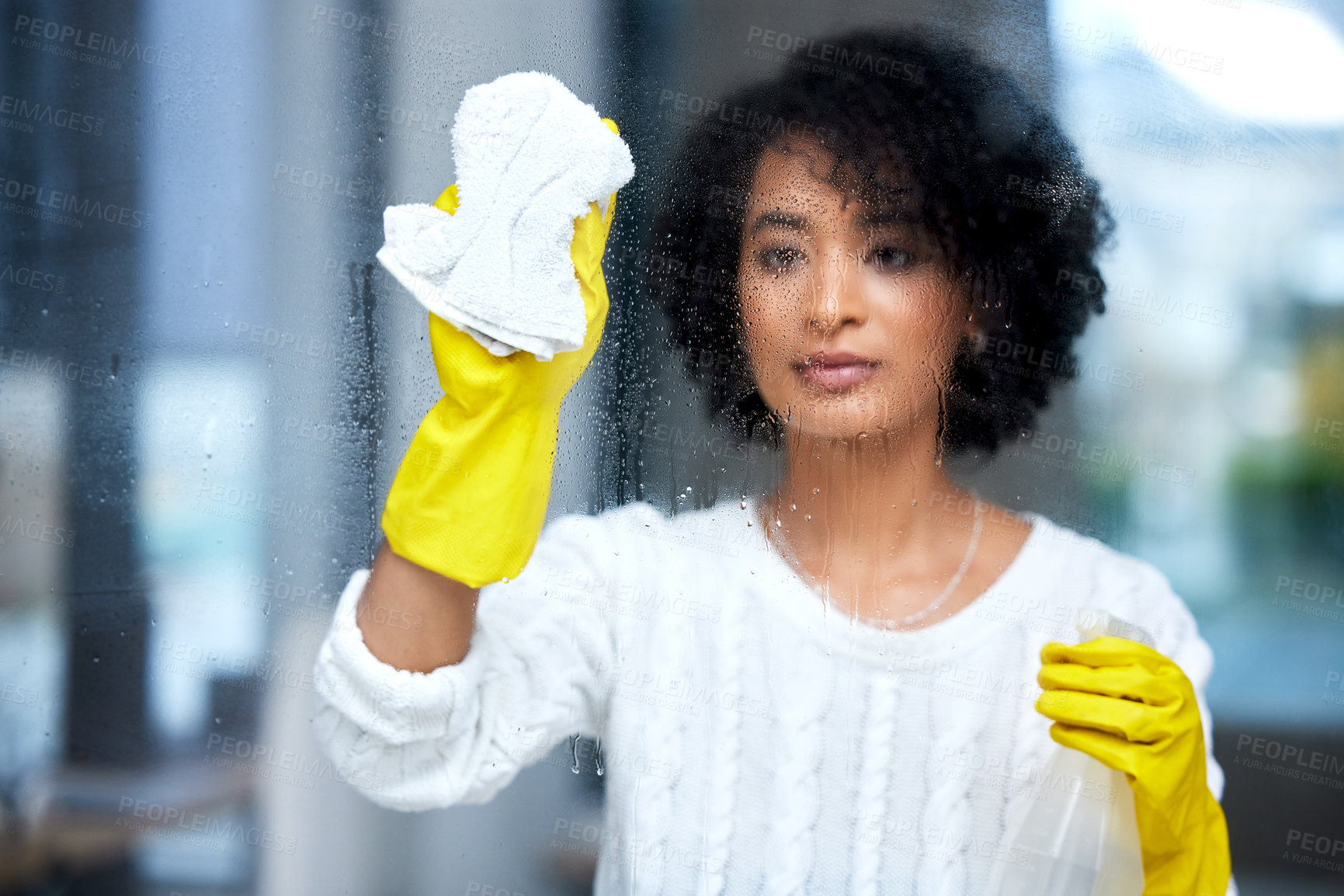 Buy stock photo Shot of a young woman cleaning her windows