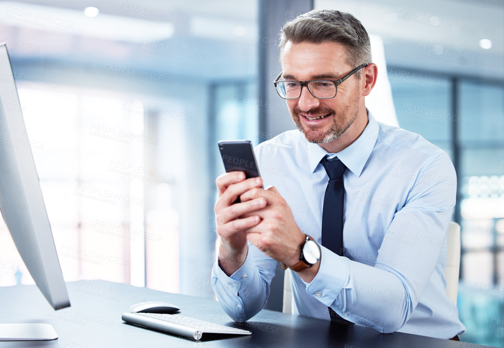 Buy stock photo Shot of a mature businessman using a phone in an office at work