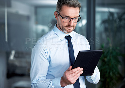 Buy stock photo Shot of a businessman using a digital tablet at the office