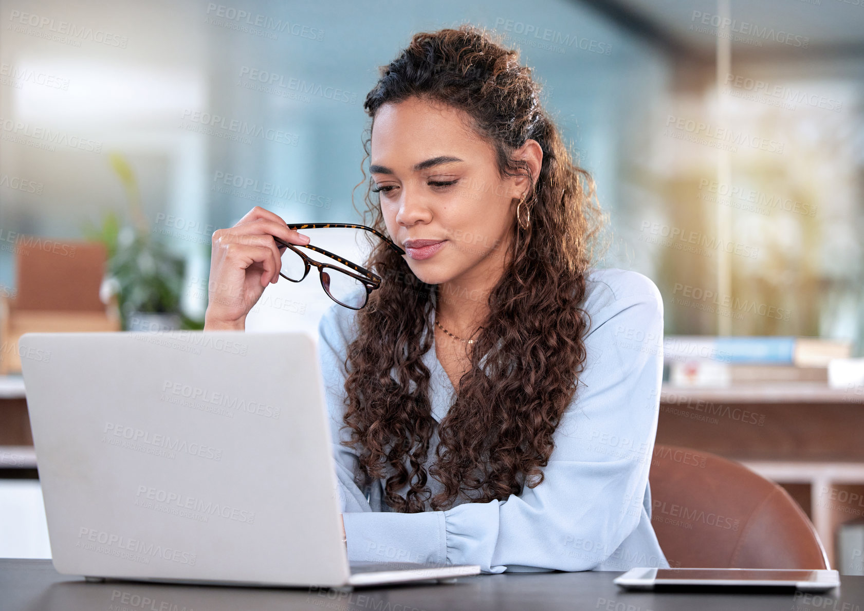 Buy stock photo Cropped shot of an attractive young businesswoman looking thoughtful while working on her laptop in the office