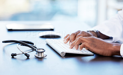 Buy stock photo Cropped shot of an unrecognizable doctor sitting alone in his clinic and typing on his keyboard