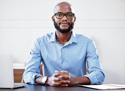 Buy stock photo Shot of a young businessman sitting at his desk