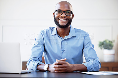 Buy stock photo Shot of a young businessman sitting at his desk