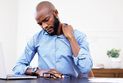 Buy stock photo Shot of a businessman suffering with shoulder pain while sitting at his desk