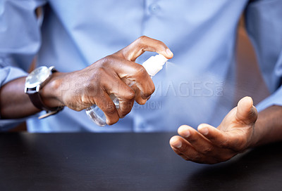 Buy stock photo Cropped shot of a businessman sanitising his hands while sitting at his desk