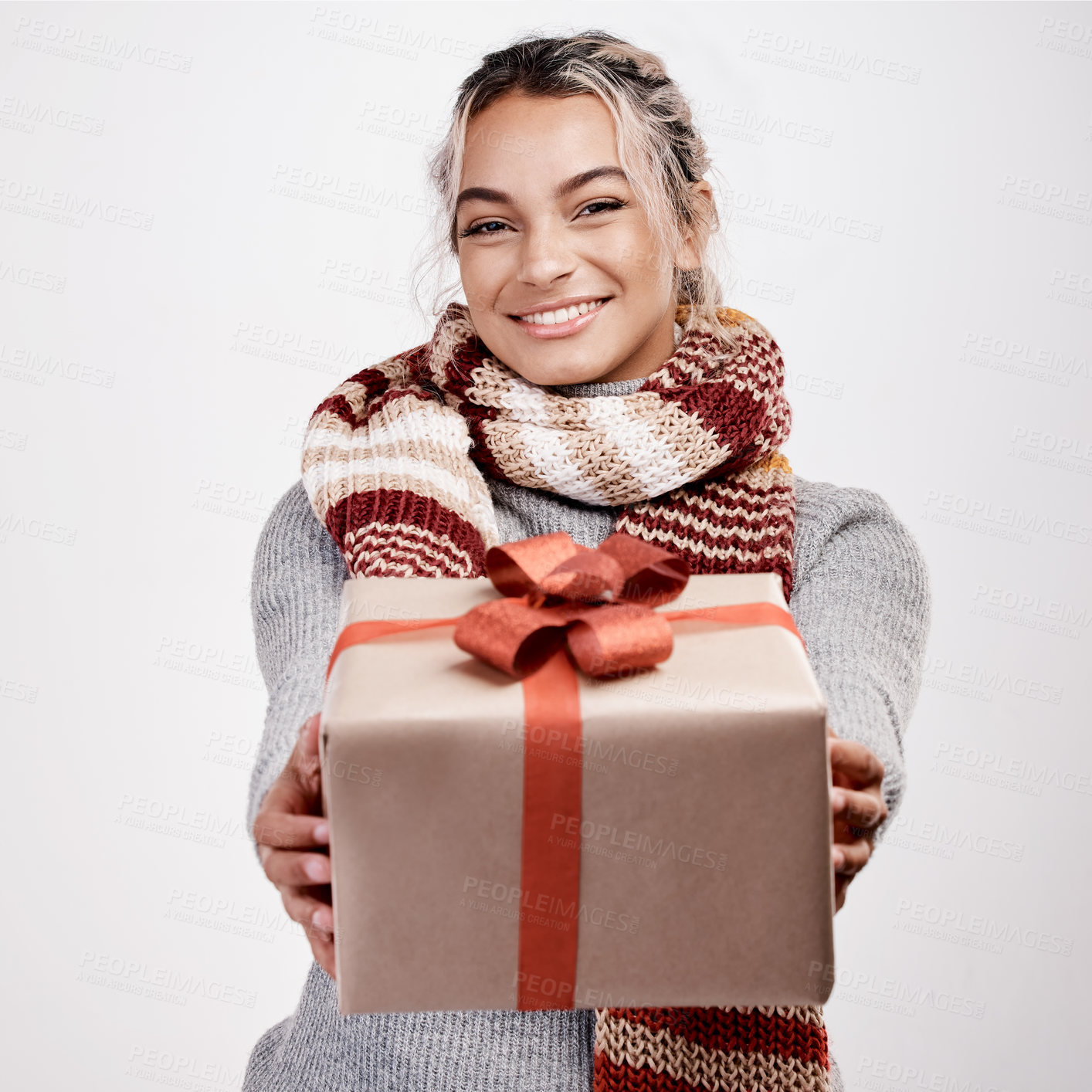 Buy stock photo Studio portrait of an attractive young woman handing you a gift while dressed in Christmas-themed attire