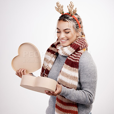 Buy stock photo Studio shot of an attractive young woman opening a heart-shaped boxed while dressed in Christmas-themed attire