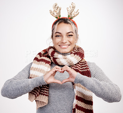 Buy stock photo Studio portrait of an attractive young woman making a heart shape with her hands while dressed in Christmas-themed attire