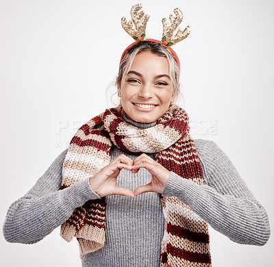 Buy stock photo Studio portrait of an attractive young woman making a heart shape with her hands while dressed in Christmas-themed attire