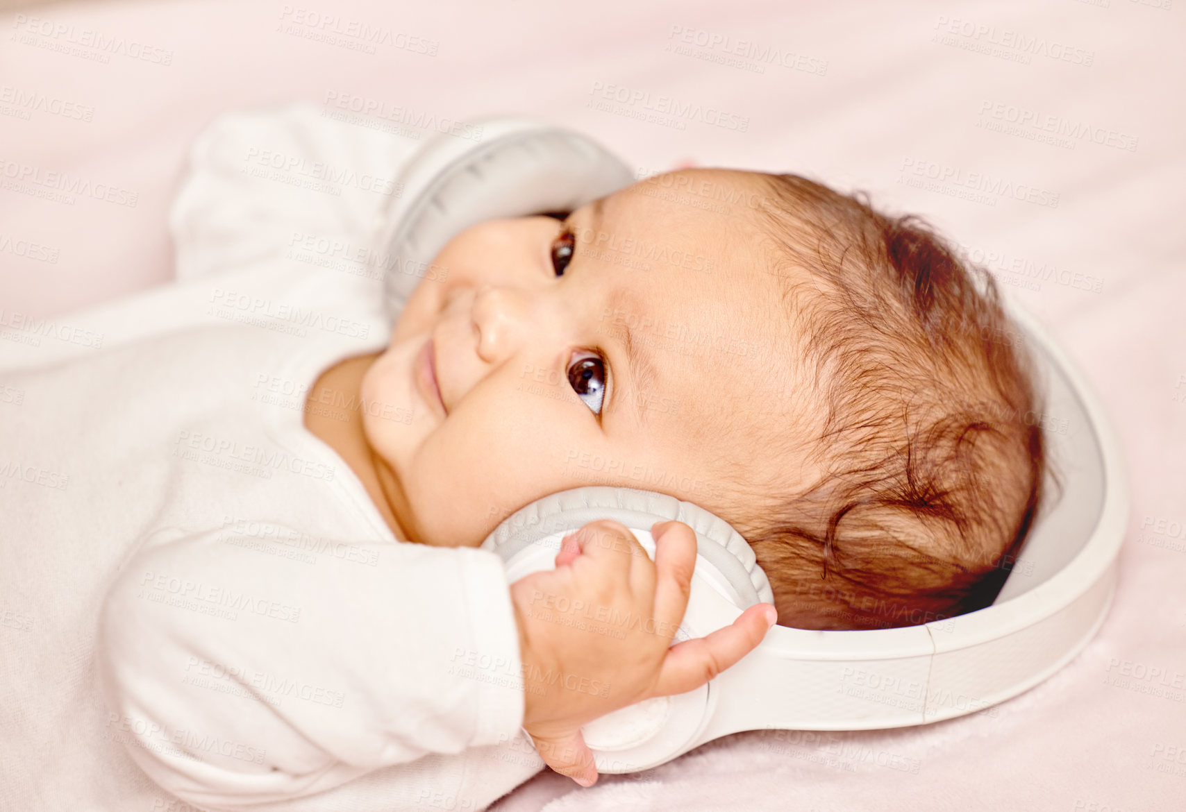 Buy stock photo Shot of a little baby lying down while wearing headphones