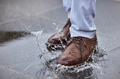Buy stock photo Shot of a unrecognizable man walking in a puddle of water outside