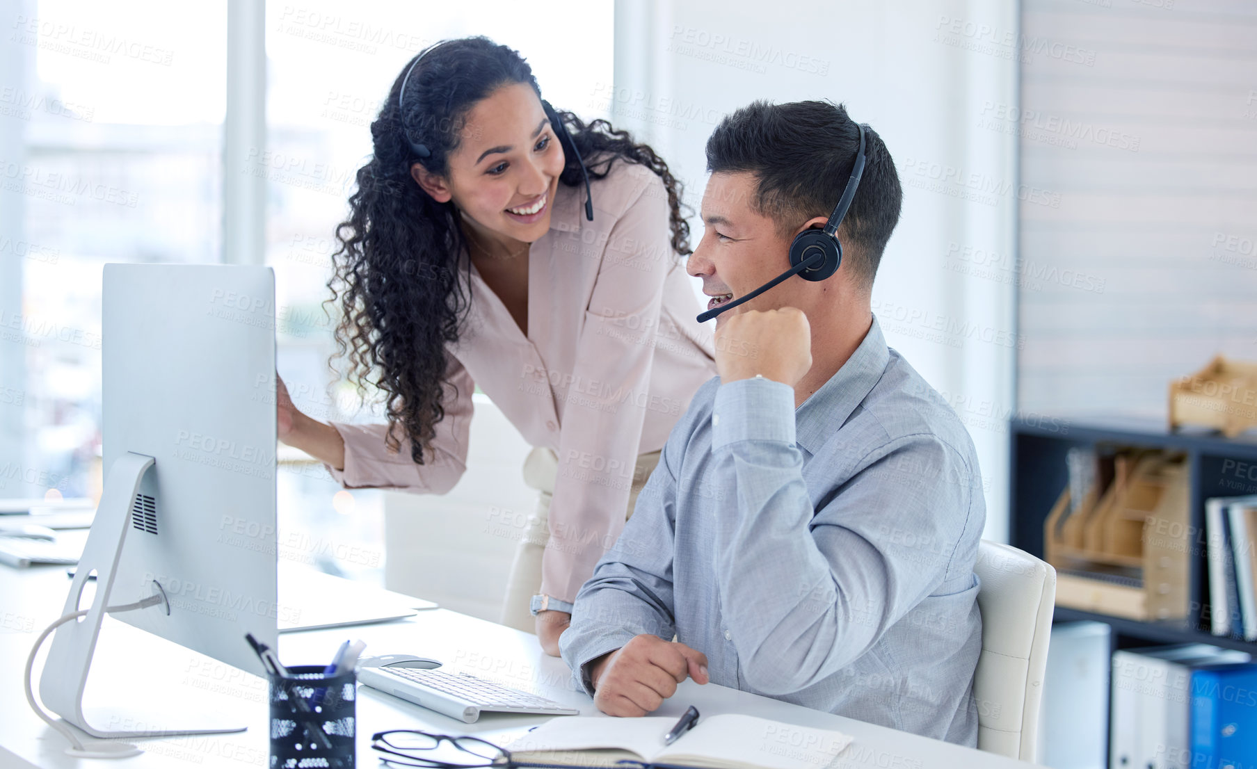 Buy stock photo Shot of two young call centre agents using a computer in the office during the day