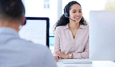 Buy stock photo Shot of a young call centre agent sitting with her colleague and using her computer