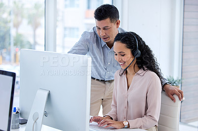 Buy stock photo Shot of two young call centre agents using a computer in the office during the day