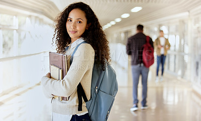 Buy stock photo Cropped portrait of an attractive young female college student standing with her textbooks in a campus hallway