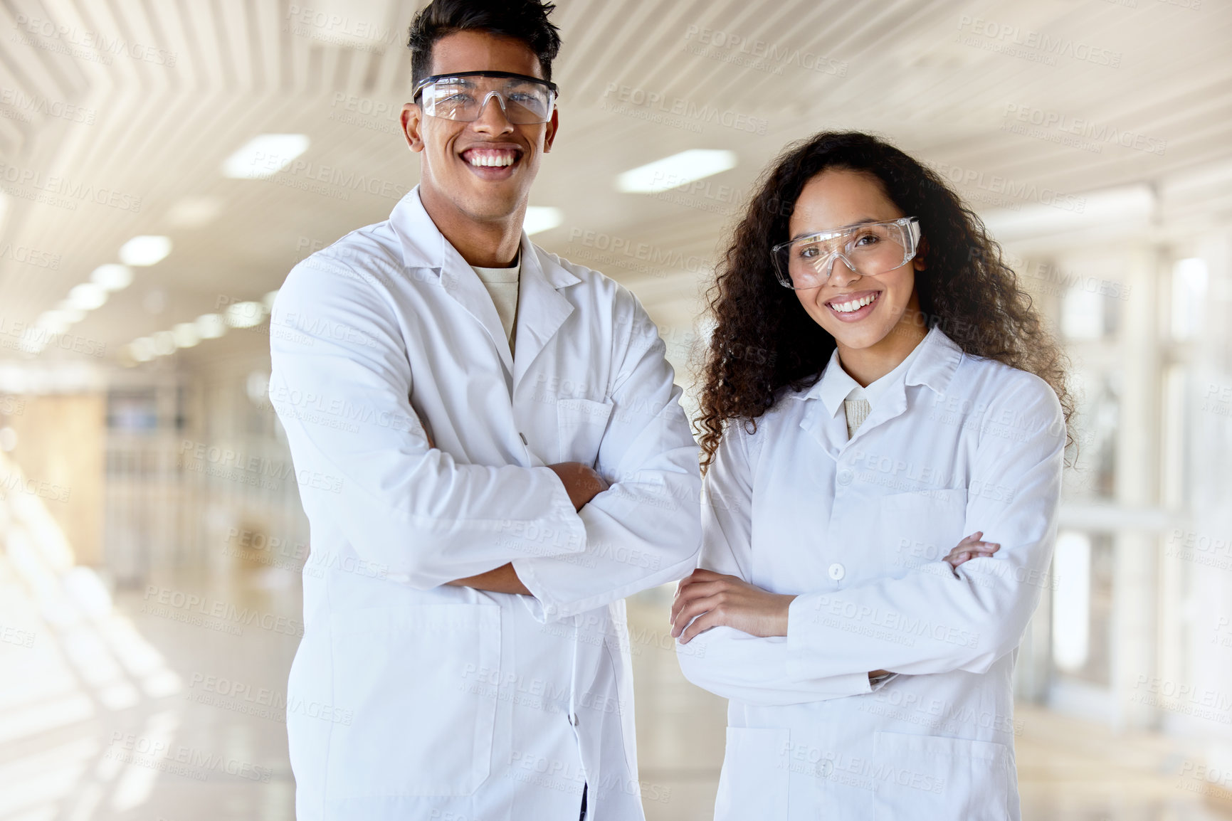 Buy stock photo Cropped portrait of two young science students standing with their arms folded in a campus hallway