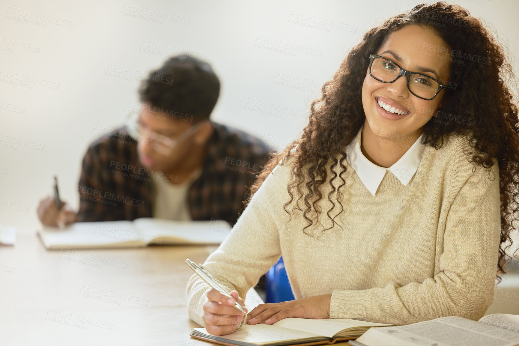 Buy stock photo Cropped portrait of an attractive young female college student writing in her notebook while sitting in class