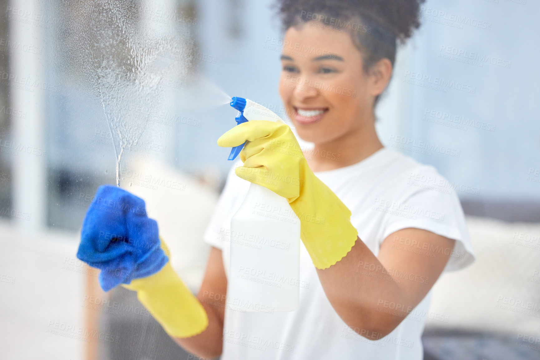 Buy stock photo Shot of a young woman cleaning the windows at home