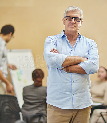 Buy stock photo Cropped portrait of a handsome mature man standing with his arms folded in the boardroom with his colleagues in the background