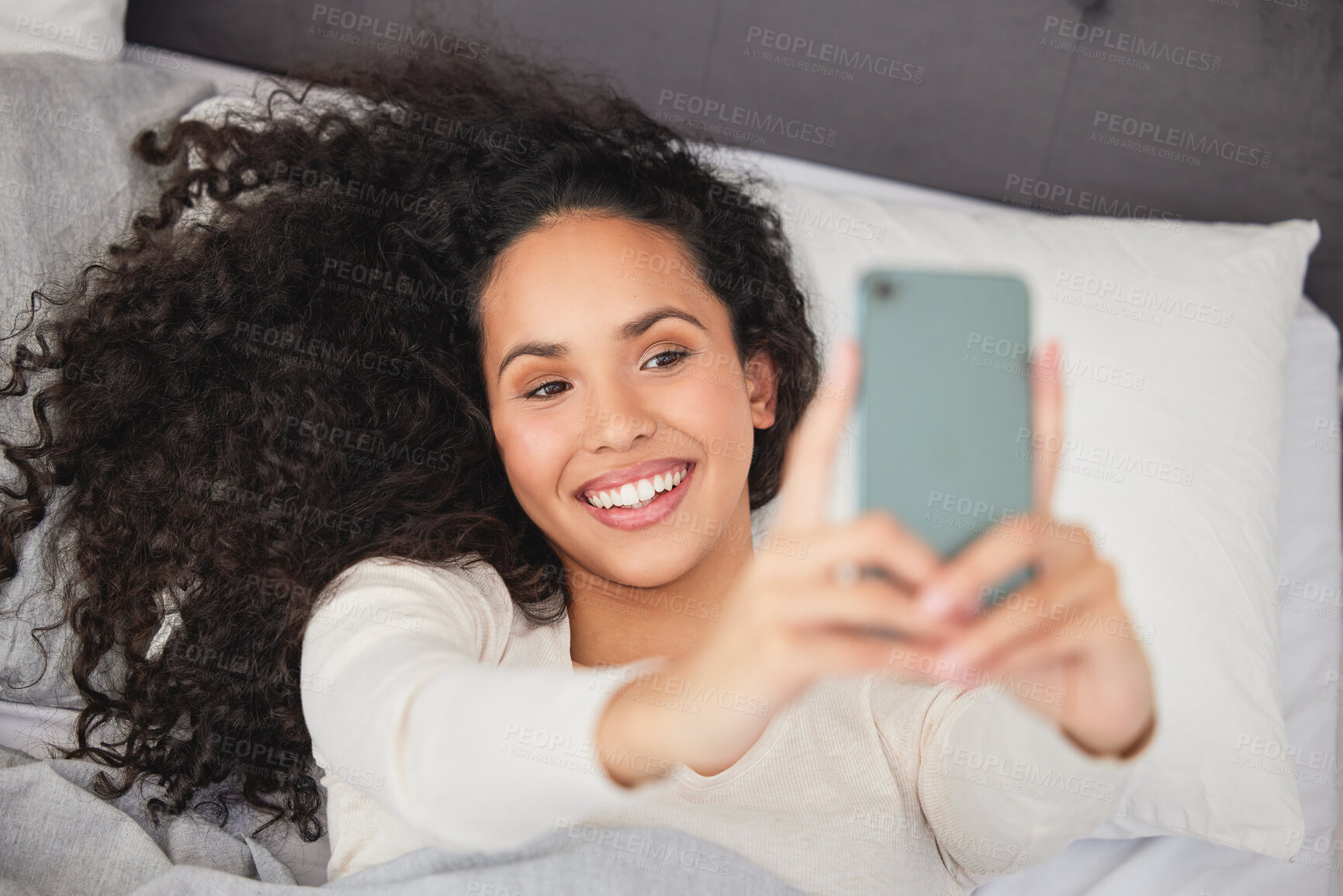 Buy stock photo Shot of a young woman laying  in bed and using her mobile phone in the morning