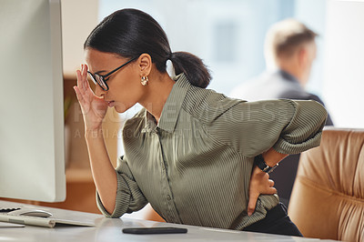 Buy stock photo Shot of a young businesswoman experiencing back pain while working in an office