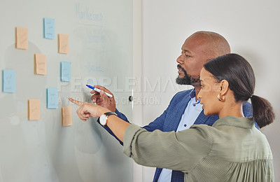 Buy stock photo Shot of two businesspeople brainstorming with notes on a  wall in an office