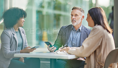 Buy stock photo Shot of a group of colleagues brainstorming ideas at a coffee shop while using their smartphones