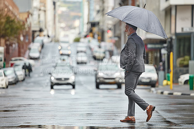 Buy stock photo Shot of a handsome businessman walking to work on a rainy day