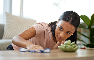 Buy stock photo Shot of a young woman cleaning a table at home