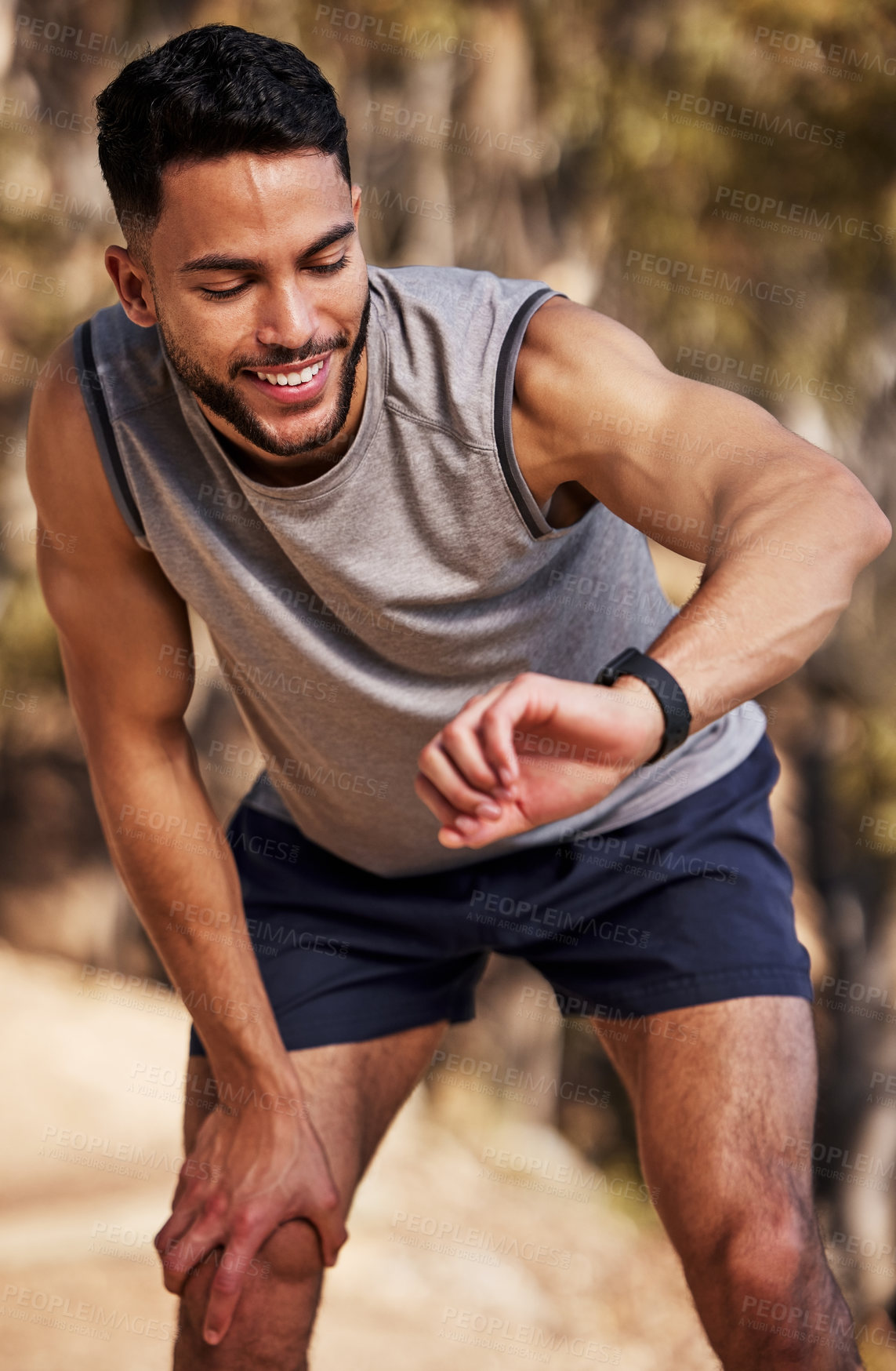 Buy stock photo Shot of a handsome young man looking at his watch during his outdoor run