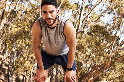 Buy stock photo Shot of a handsome young man taking a moment to catch his breath during his outdoor run