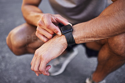 Buy stock photo Cropped shot of an unrecognizable man crouching down and setting a timer on his watch before running outside