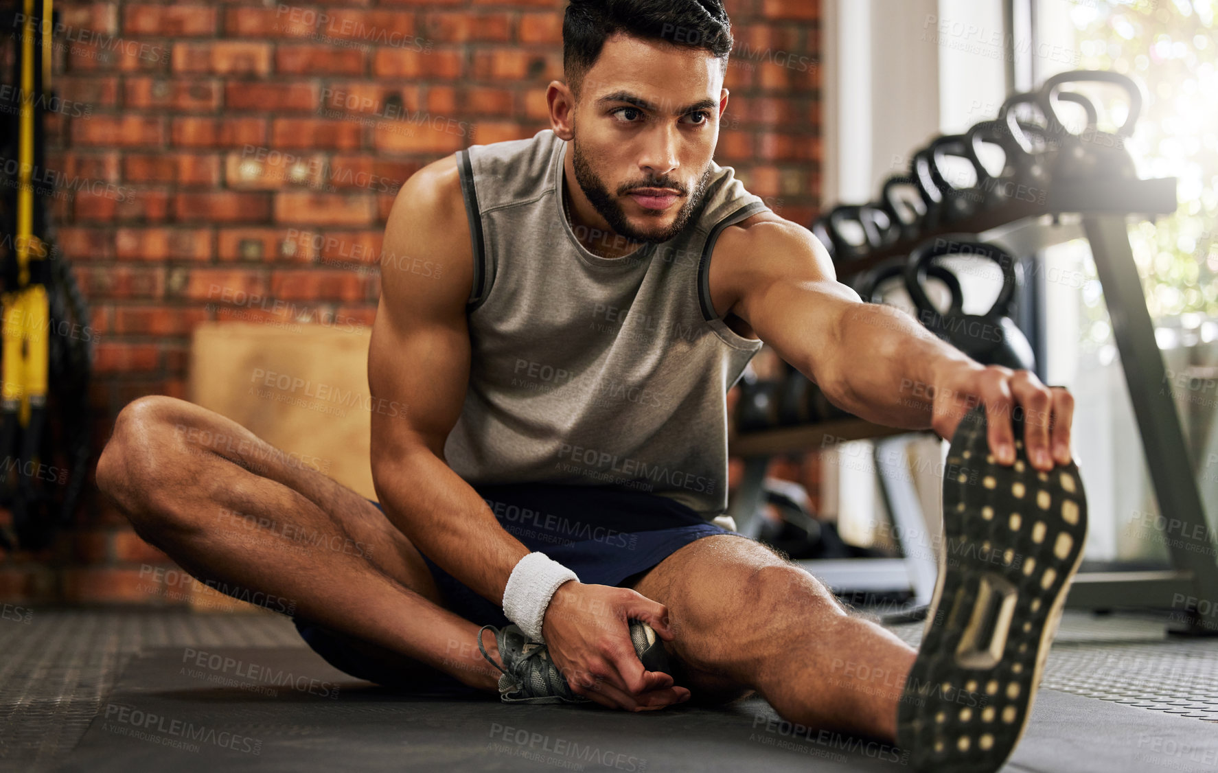 Buy stock photo Gym, man sitting and stretching legs for workout warm up, motivation and fitness mindset with hand on foot. Focus, commitment and male athlete on floor, leg stretch at sports club for exercise goals