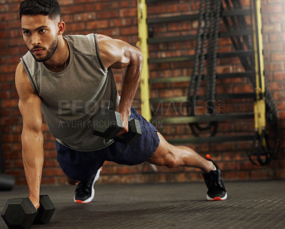 Buy stock photo Shot of a young man working out with dumbbells in a gym