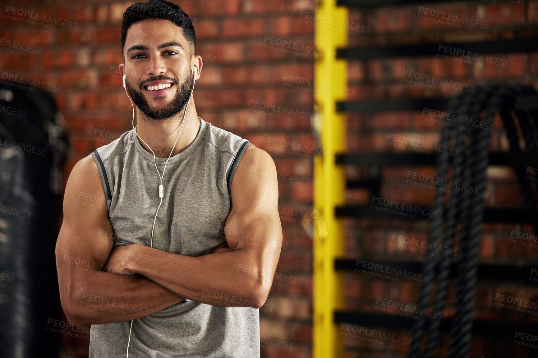 Buy stock photo Fitness, earphones and portrait of man in gym, arms crossed and confident smile in mockup space. Happiness, workout and happy face of bodybuilder streaming music for health, indoor training and pride