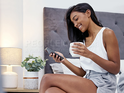Buy stock photo Coffee, girl and phone for reading, bedroom and relax in morning, smile for post online, app and house. Weekend, internet and mobile for Indian woman, happy and novel in website, connection and home