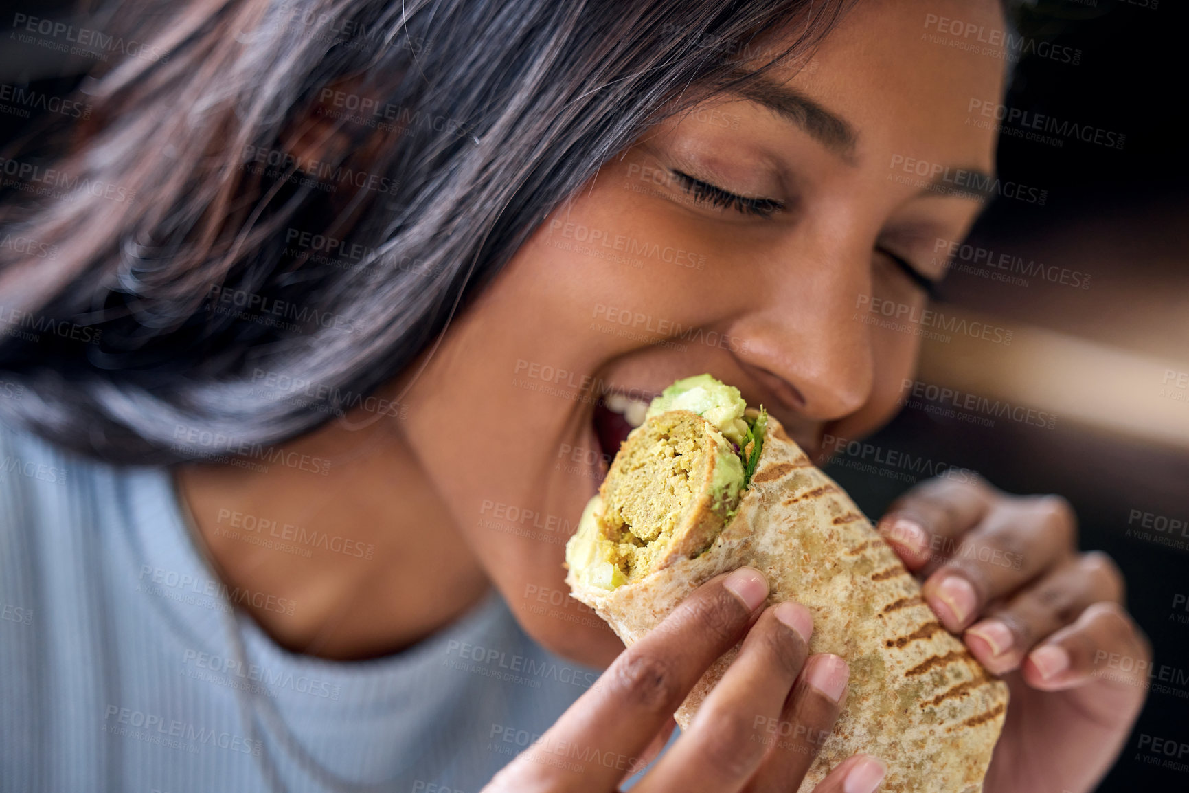 Buy stock photo Shot of a young woman enjoying a wrap during lunch