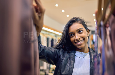 Buy stock photo Shot of a young woman browsing through shopping rails