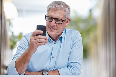 Buy stock photo Shot of a mature businessman sitting alone in the office and using his cellphone