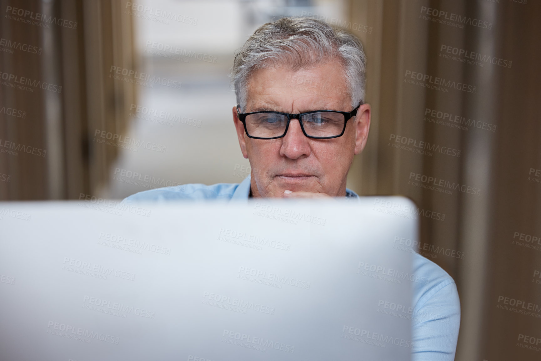 Buy stock photo Shot of a mature businessman sitting alone in the office and using his computer