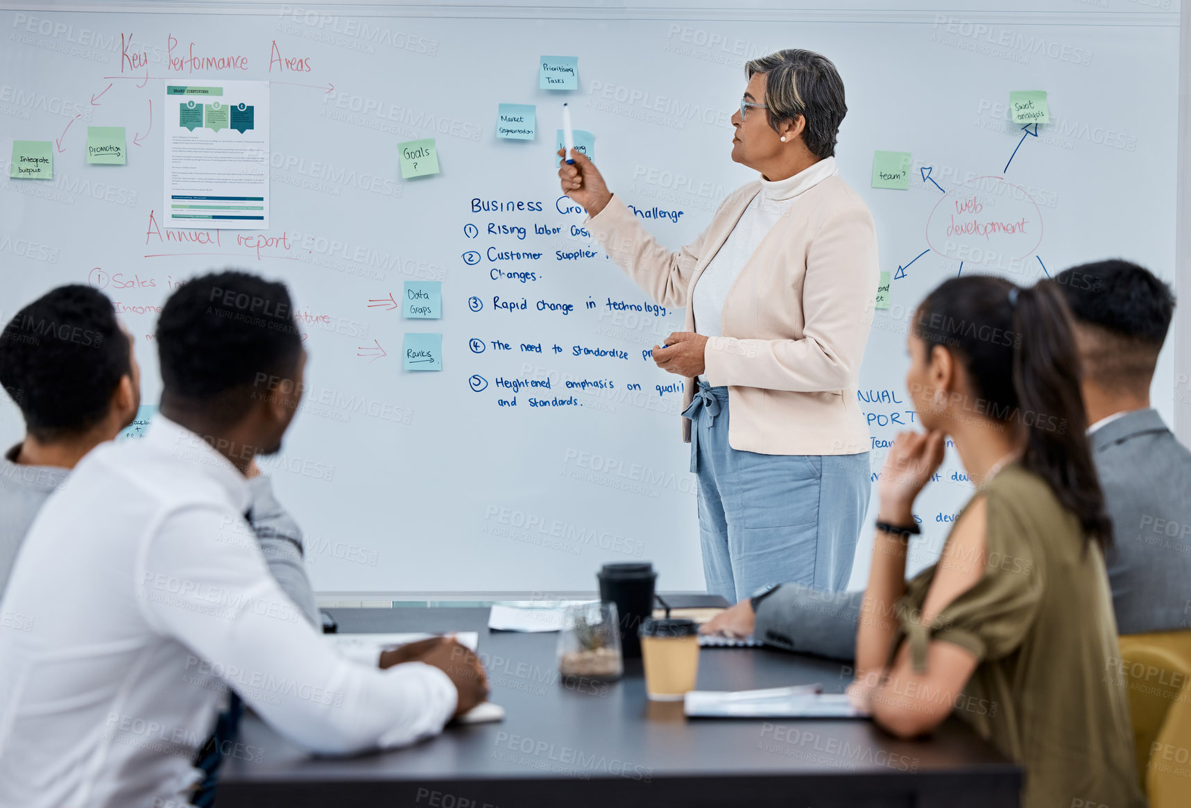 Buy stock photo Shot of a mature businesswoman using a whiteboard during a presentation to her colleagues in an office