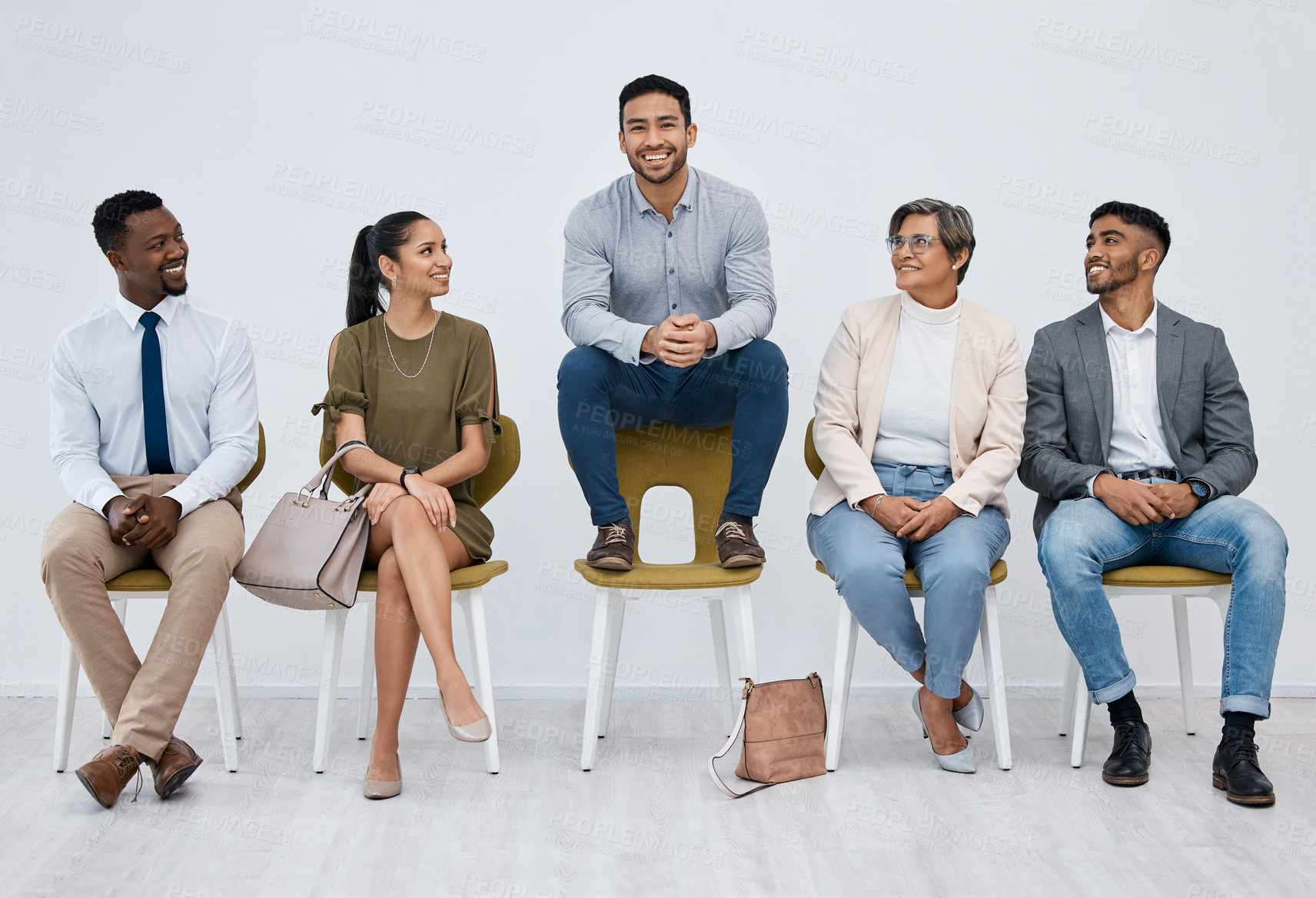 Buy stock photo Studio portrait of a young businessman sitting on a chair alongside candidates against a white background